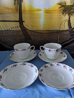 Two teacups on saucers with three extra matching saucers