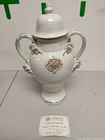 Front view of ceramic urn with lid and certificate