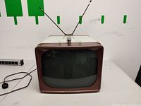 Front view of GE portable CRT television showing screen, antenna, and power cord