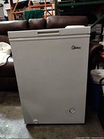 Front view of white chest freezer showing recessed handle and Midea logo