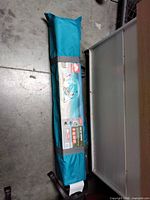 Full view of teal carry bag containing shelter