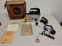 Full lot view showing Geiger counter, box, manuals, strap, adapter, earpiece and tag