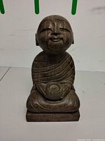 Front view of seated resin Buddha statue on plinth