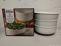 Box of Trudeau 3-piece porcelain serving bowl set beside stacked bowls