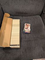 Long cardboard card storage box filled with trading cards plus separate rubber-banded stack
