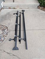 Two long black steel rails with clamp ends and center legs, hardware visible