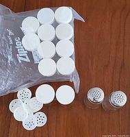 All lids, shaker inserts, two spice jars and two salt & pepper shakers on tabletop