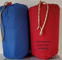 Two stuff sacks, red and blue, standing upright showing size and colour