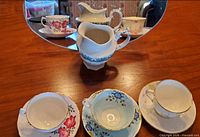 Full lot: three cup & saucer sets and jug reflected in mirror