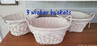 Three white wicker baskets with liners displayed side by side