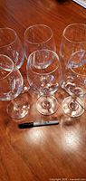 Six crystal wine glasses on wooden surface with marker for scale