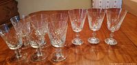 Nine stemmed crystal goblets with two distinct cut patterns grouped on table