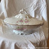 Side view of covered porcelain serving dish showing floral pattern, handles, lid and base