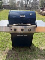 Front view of Vermont Castings Signature Series three-burner natural gas grill showing hood, side shelves, control panel and cabinet base