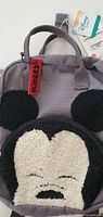 Front view showing Mickey Mouse chenille face and ears on grey backpack