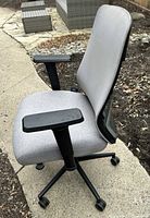 Left side view of the chair showing fabric seat, mesh back, armrests, base and casters