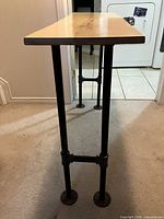 Side profile showing slim live edge wood top and iron pipe leg construction