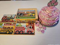 Group shot of four puzzles, storage case and tiered cake toy