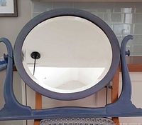 Front view of round mirror in wooden swivel frame