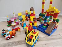Wide view of assorted Duplo sets: Percy train on track, school bus, cake pieces, farm bricks, slide, arch