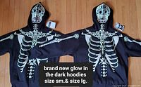 Both hoodies laid flat showing front skeleton design and size tags