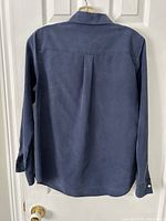 Back view of navy blouse showing long sleeves, hem shape, back pleat