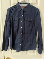 Full front view of navy Tommy Hilfiger blouse hanging, shows overall condition and style