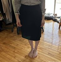 Front view of black pencil skirt worn by model