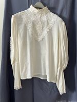 Front view of off-white lace blouse