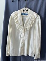 Full view of cream blouse on hanger