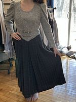 Front view of grey bouclé bodice and check skirt dress on model