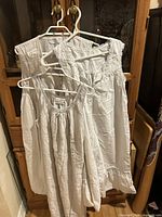 Three white cotton nightgowns on hangers showing overall style and quantity