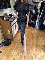 Front view of black satin evening gown on model showing lace bodice, sequins, puff sleeves, high side slit