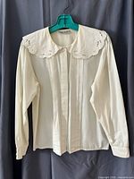 Front view of white blouse showing collar, pintucks, concealed placket, long sleeves