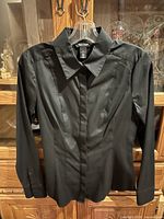 Front view of black tailored blouse on hanger