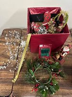 Overview showing red box with fabric ornaments, gold sprays, Santa figurine, greenery ring and silver branch
