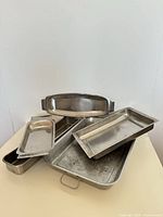Stack of six stainless steel trays of varying sizes and depths