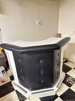 Front view showing black vinyl tufted panel, white sides, chrome-tone base rails