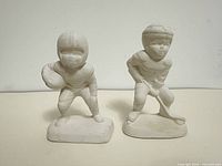Front view of both unfired bisque sports figurines