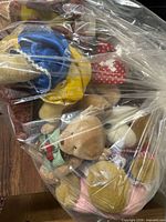 Bag showing assorted stuffed animals including teddy with blue/yellow dress and others