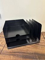 Overall view of black metal document sorter showing two horizontal trays and four vertical dividers