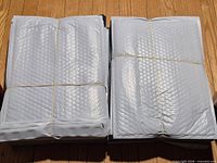 Two bundles of grey padded bubble mailers stacked side by side