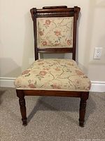 Front view of wooden chair showing upholstery and turned legs