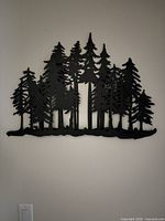 Frontal view of entire black metal tree silhouette wall art hung on wall