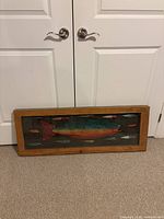 Full view of framed artwork showing central fish and surrounding lures