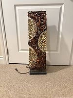 Full front view of lamp showing woven rattan body, metal base and cord