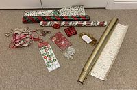 Group shot of wrapping paper rolls, ribbons, stickers, gift box, cord and decorative items laid on carpet