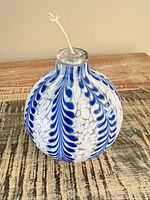 Front view of blue and white hand-blown glass oil candle