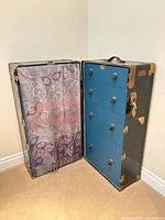 Trunk open showing blue drawers and hanging compartment