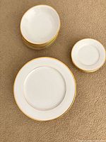 Stacks of gold-rimmed dinner plates, bowls and small plates shown from top
